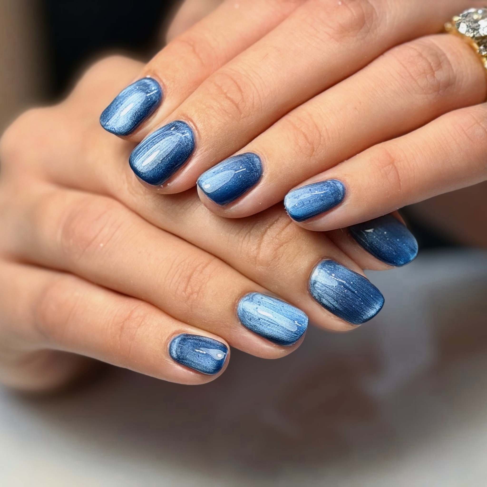 Short gel nails in a glossy blue chrome finish