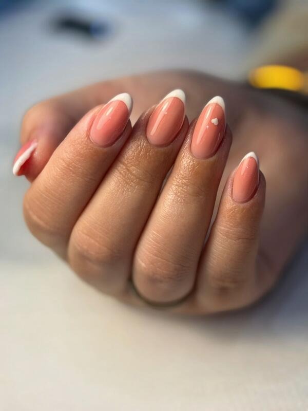 Almond nails with white French tips and a small heart