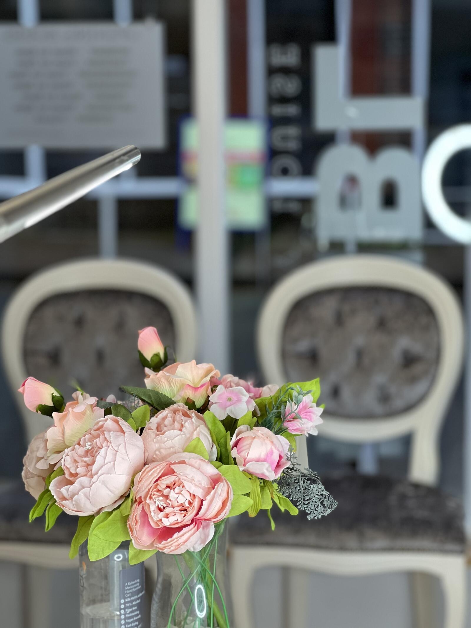 Pink peonies in front of the velvet chairs at the original salon in Leighton Buzzard